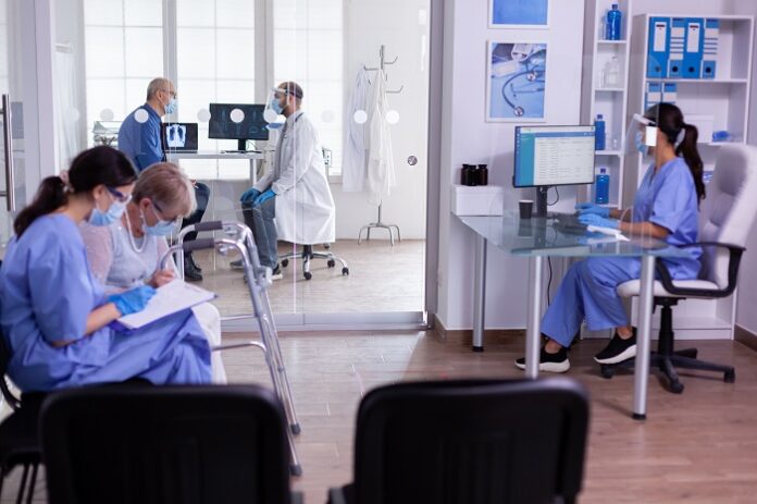 Nurse checking appointment form of old disabled woman with walking frame