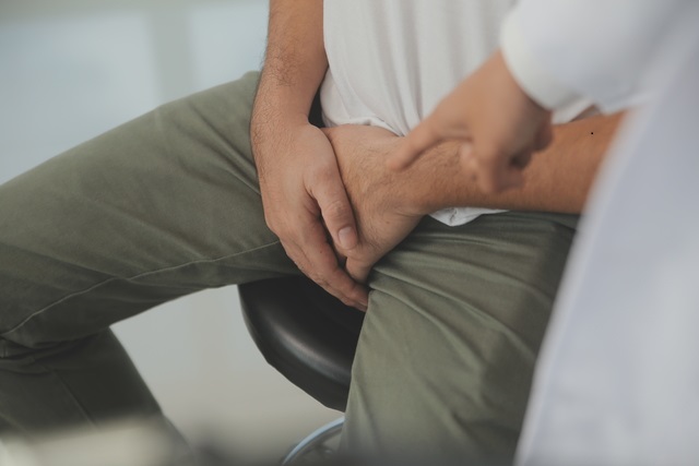 Male diseases. Man presses hands to his groin and suffering from